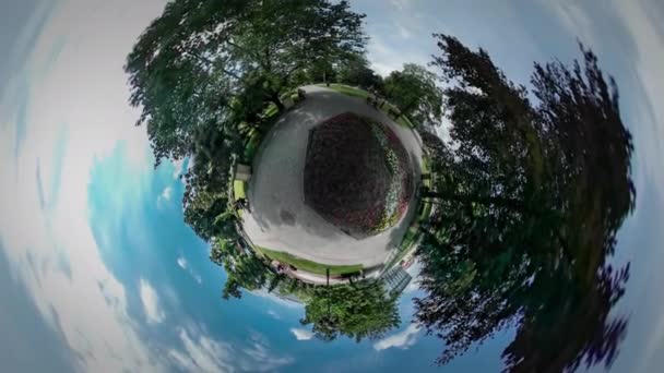 360vr Video mensen wandelen door trottoirs in stadspark onder de bomen bloembedden groene verse bomen straatstenen blauwe hemel witte wolken Opole Polen — Stockvideo