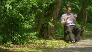 Adam Tıklanma bankta oturan bir Tablet Park sohbet Forex gayrimenkul satın alma Internet alışveriş harcamak zaman doğa taze yeşil ağaçlar yaz gün