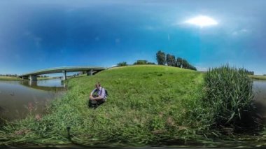 360vr Video adam Backpacker nehir Reed su turist tarafından bir yere köprü üzerinde oturan bir dinlenme vardır doğa yaz gün ortasında güneş mavi gökyüzü parlıyor