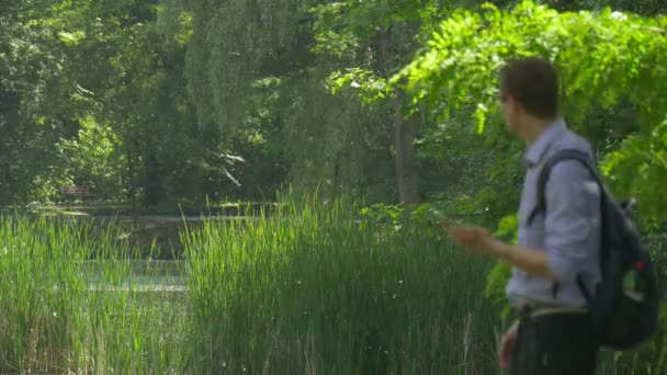 Man met Smartphone komt Texting zomer Park Holding een mobiele telefoon en chatten Backpacker is wandelen in de natuur fris groen bomen zonnige dag — Stockvideo