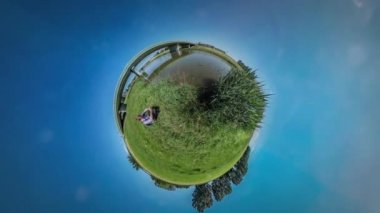 360vr Video adam bir çim Köprüsü nehir Reed su turist tarafından aracılığıyla oturup sırt çantası ile sahip bir dinlenme doğa yaz gün ortasında güneş mavi gökyüzü parlıyor