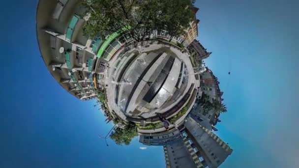 360Vr Video Turista è seduto vicino a una fontana della città Backpacker Cityscape Le auto sono guidate dalla strada Case a più piani Sole splende Blue Sky Green Trees — Video Stock