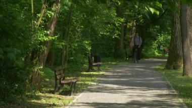 Backpacker kürsüye Park sokak alır Off Onun Bisiklet gidiş Bisiklet durur oturup bir tezgah altında ağaçlar turist var dinlenme spor güneşli yaz at binme