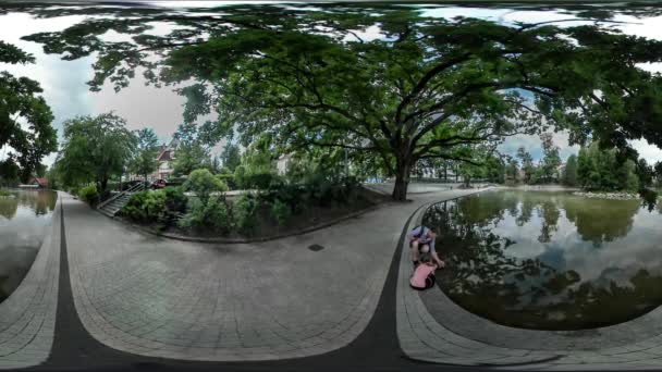 360vrビデオお父さんと子供は、池市の日オポールパーク路地家族の父は公園夏の曇りに乗ってサイクリストを再生する子供と座っています — ストック動画