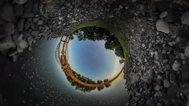 360VR Video hombre está corriendo del ferrocarril Puente Río Verde árboles piedras de un banco en una ondulación superficial en agua verde hierba atardecer azul cielo soleado día de verano — Vídeo de stock