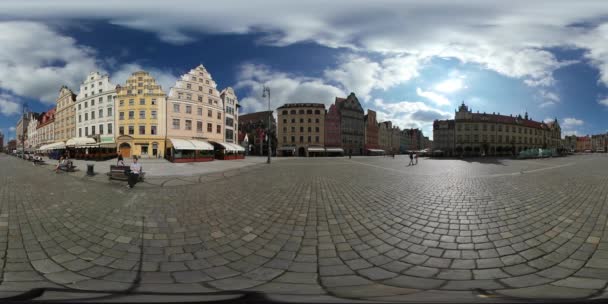 360vr Video Mann setzt sich auf die Bank alten Platz Breslau sonnigen Tag Vintage-Gebäude Touristen spazieren durch den Platz mit Pflastersteinen Stadtbild — Stockvideo