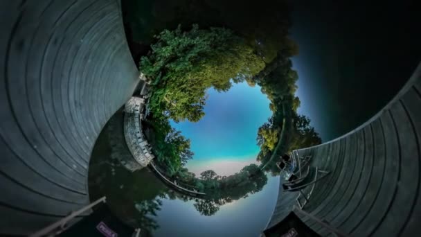 Vidéo 360Vr Les gens qui font du vélo sur un quai Les cyclistes passent du temps près de l'étang de la rivière Masse en bois sur de l'eau lisse Deux personnes dans des chaises longues Crépuscule Arbres verts — Video