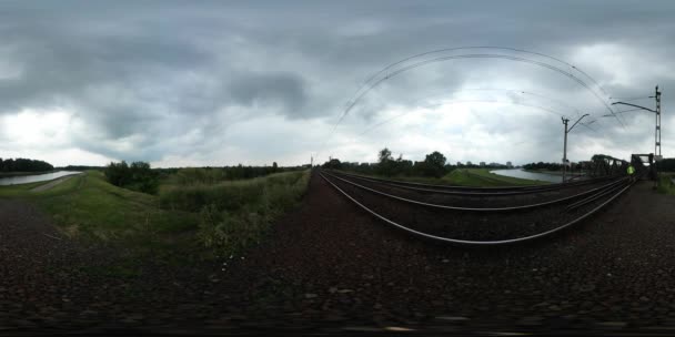 360vr 视频男子步行在铁路在绿地铁路架空线电气化系统云景绿树在地平线多云的一天夏天 — 图库视频影像