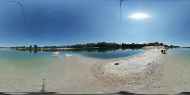 360Vr Video El hombre está sentado en la barra de arena en el agua Panorama esférico El cielo se refleja en el agua El hombre en el campo Naturaleza salvaje Cielo azul claro Día soleado — Vídeo de stock