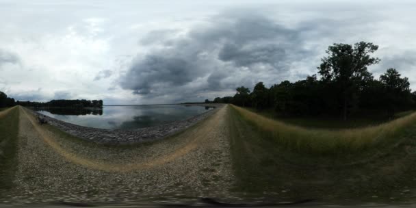 360vr Video způsobem silnici podél pobřeží zataženo den suché trávy zelené stromy rostou pěšina mraky jsou plovoucí vodnaté povrchu Horizont — Stock video