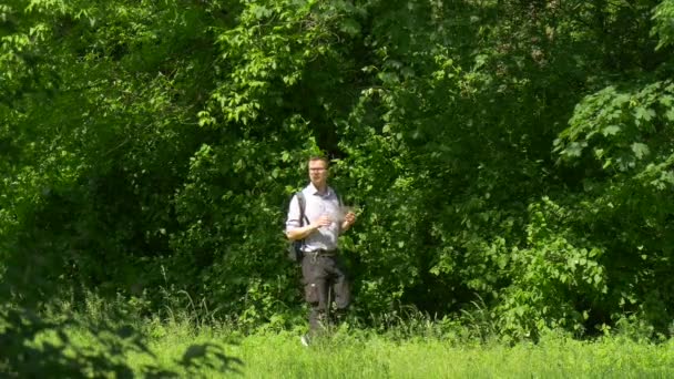 Hombre con tableta virtual en Green Park sosteniendo una tableta Pasa tiempo en la naturaleza Árboles verdes frescos Soleado día de verano — Vídeo de stock