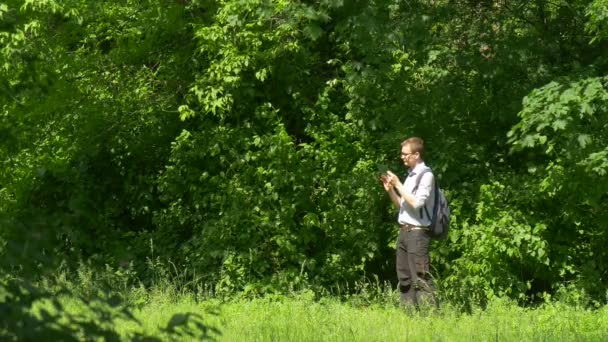 Férfi virtuális tabletta tabletta időt a természet friss zöld fák napsütéses nyári napon Green Park gazdaságban — Stock videók