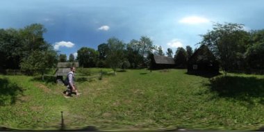 360vr Video turist Courtyard kulübe ile Reed çatı evler eski köy ihtiyar, yürüme gözlemleyerek terk edilmiş rustik evlerin yeşil ağaçlar orman çim güneşli olduğunu