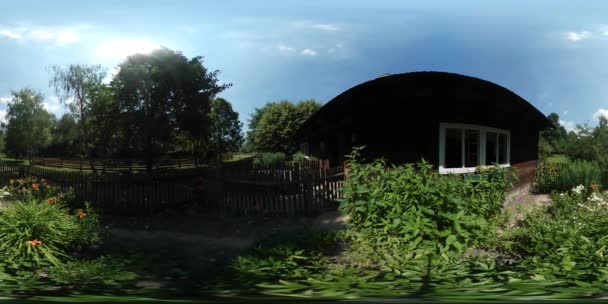 Vídeo 360Vr Turista Perto da Casa Telhado Semicircular Velho Aldeia Homem Observando Casas Rústicas Os pátios são cercados com Palisade Árvores Verdes Floresta Grama Ensolarada — Vídeo de Stock