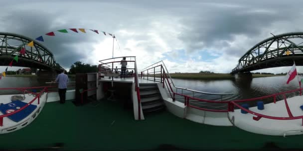 360vr Videomänner auf dem Deck des Vergnügungsschiffs Menschen schweben an der Oder unter der Brücke grüne Bäume und Gras auf beiden Seiten des Flusses — Stockvideo