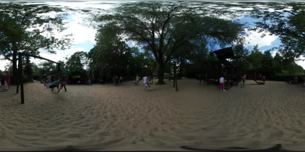 Video kinderen van de 360vr op Speeltuin stadspark dag Opole wandelen door zand gezinnen hebben een Rest mensen zijn op zoek na baby's kinderen schommels trap groene bomen — Stockvideo