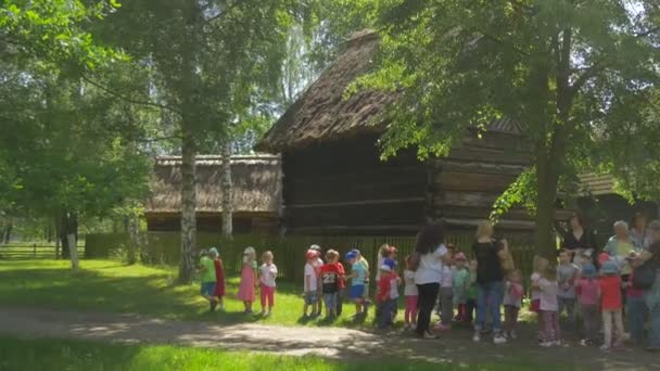 Grupa dzieci wśród starych drewnianych domów w lesie — Wideo stockowe