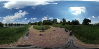360vr Video adam bir güneşli gün bisikletçi bisiklet fayans banklar Alley Backpacker durak yakın turkuaz Gölü Parkı güneşli gün parke yapılmış yolda Gets