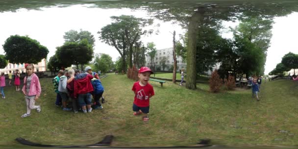 360Vr Vídeo Jardim de infância Graduação Crianças na grama no parque Crianças na praça estão brincando juntas e se comunicam Dia ensolarado de verão Opole Polônia — Vídeo de Stock