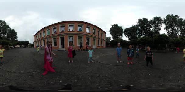 360Vr Vídeo Jardim de infância Graduação Crianças saltando ao redor no quintal Meninos e meninas de bom humor estão correndo ao redor do dia de verão Opole Polônia ao ar livre — Vídeo de Stock