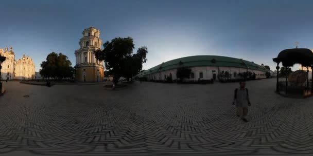 360 Вр видео человек возле колокольни кусок старой стены Кобблстоун Киево-Печерской Лавры Турист смотрит на исторические религиозные здания закат — стоковое видео