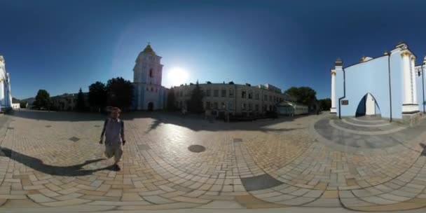 360 Vr Video Man снимает монастырь Майкла Панораму колокольни Кобблстоун Сквер в солнечный летний день Люди идут зеленая трава лужайка голубое небо — стоковое видео