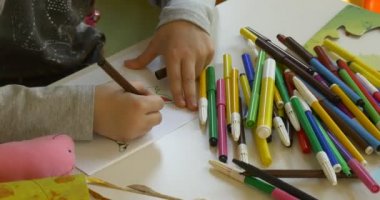 Portakal sandalye beyaz bir masanın arkasında çocuk oturur.