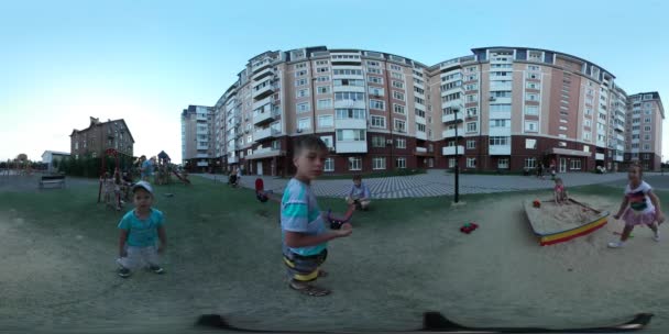 360Vr Video Niños haciendo muecas en el patio de recreo Día de la ciudad de Kiev Casa residencial Los niños están corriendo jugando en Sandbox Cerca de edificios de varios pisos por la noche — Vídeo de stock