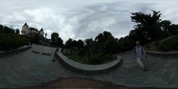 360Vr Video Man Walking Filming Puppet Show Theatre Kiev Cloudy Day Park Around the Old-Style Modern Building Small Pond Trees' Silhouettes Pavement — Stock Video