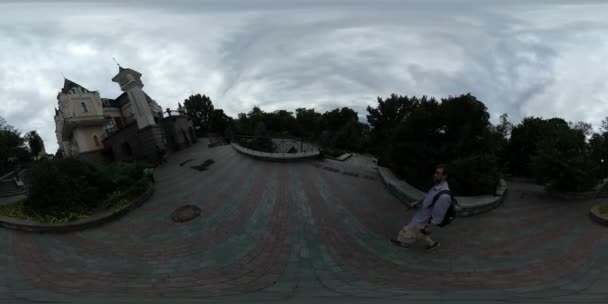 360Vr Video Hombre Filmando Teatro de marionetas Kiev Cloudy Day Hombre Subiendo las escaleras Edificio moderno de estilo antiguo Pequeños árboles de estanque 'Siluetas Pavimento — Vídeo de stock