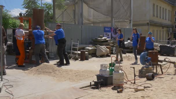 Группа строителей перемещает тяжелую промышленную печь на строительную площадку — стоковое видео