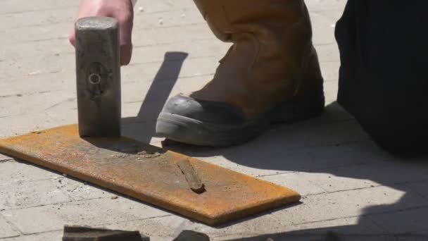 Man breekt metalen plaat met hulp van een hamer — Stockvideo