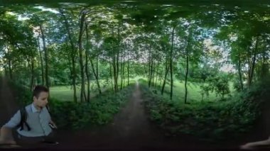 360vr Video adam kendini Park sokak yeşil video çekme ağaçlar tarafından patika güneş parlar aracılığıyla dalları adam turist Backpacker ağaçları arasında yürüyüş.