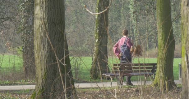 Ο υψηλής ενήλικος άνθρωπος έχει ένα υπόλοιπο σε ένα ξύλινο παγκάκι στο κέντρο του ένα πάρκο της πόλης — Αρχείο Βίντεο