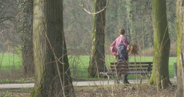 A magas felnőtt ember van a többi City Park szívében egy fapadon — Stock videók