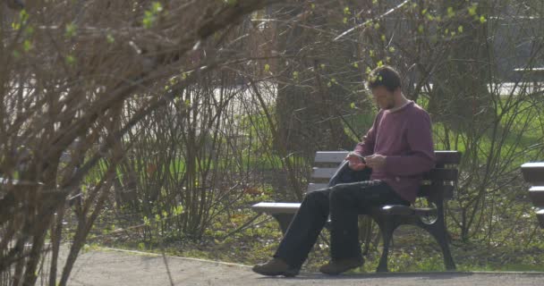 Le touriste s'assoit sur un vieux banc en bois dans le parc central d'une ville d'Opole (Pologne) ) — Video