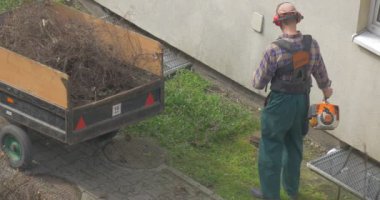 Adam el ile çim biçme makinesi elinde tutar.