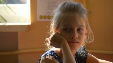 Küçük kız okulda okul masa başında oturur