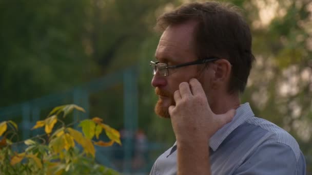 A vörös szakállas férfi áll egy Opole City Park szívében — Stock videók