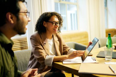 İki yetenekli profesyonel, işbirliğini geliştirmek için dijital araçlar kullanarak verimli bir toplantıda.