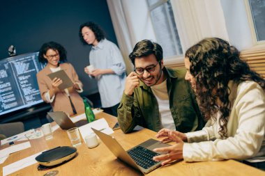 Ekip laptoplar, gazeteler ve kahveyle birlikte masanın etrafında sprint teftişi yapıyor.,