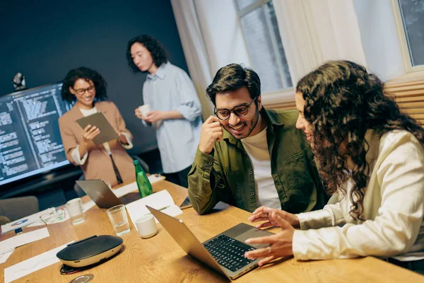 Ekip laptoplar, gazeteler ve kahveyle birlikte masanın etrafında sprint teftişi yapıyor.,