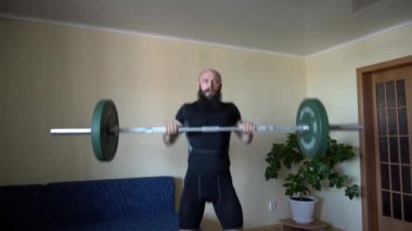 Karantina sırasında evde halter egzersizi yapan genç adam.