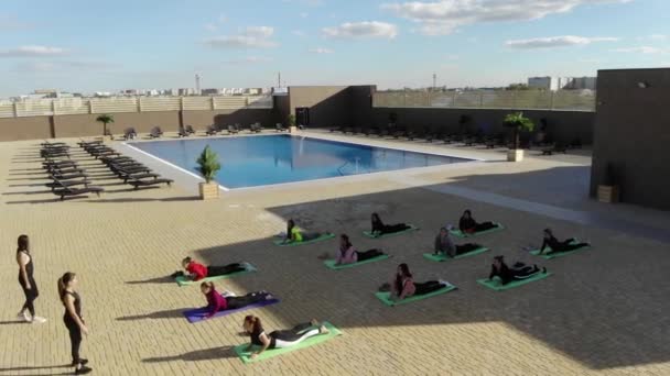 Το μάθημα γιόγκα κάνει ασκήσεις τεντώματος κοντά στην πισίνα, καθαρό αέρα και σωματική δραστηριότητα. Ενεργός τρόπος ζωής. — Αρχείο Βίντεο
