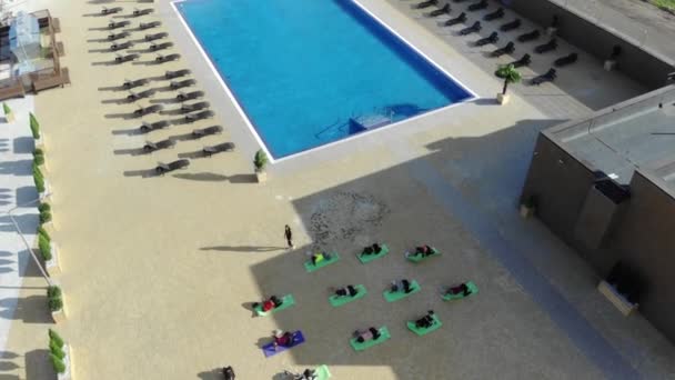 Un grupo de chicas hermosas jóvenes realizan ejercicios de yoga al aire libre cerca de la piscina. Estilo de vida activo. — Vídeo de stock