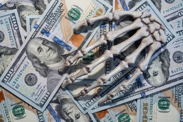 Skeleton hand lying on the dollars. Royalty Free Stock Photos