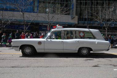 Toronto, ON, Kanada - 12 Ekim 2025: Beyaz antika bir acil durum aracı kaldırımdan izleyicilerin izlediği bir geçit töreninde şehir caddesinde ilerliyor.