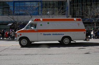 Toronto, ON, Kanada - 12 Ekim 2025: Beyaz ve turuncu bir Toronto ambulansı geçit töreninde bir şehir caddesinde ilerliyor.