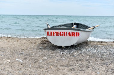 Toronto, ON, Kanada - 12 Ekim 2025: Beyaz bir cankurtaran botu denizin yanındaki çakıllı bir sahilde, güvenlik görevine hazır..