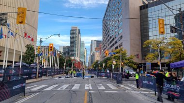 Toronto, ON, Kanada - 18 Ekim 2025: Yarış engelleri olan boş bir şehir caddesi uzun bir ofis kulesinin önünde maratonun önünde duruyor.
